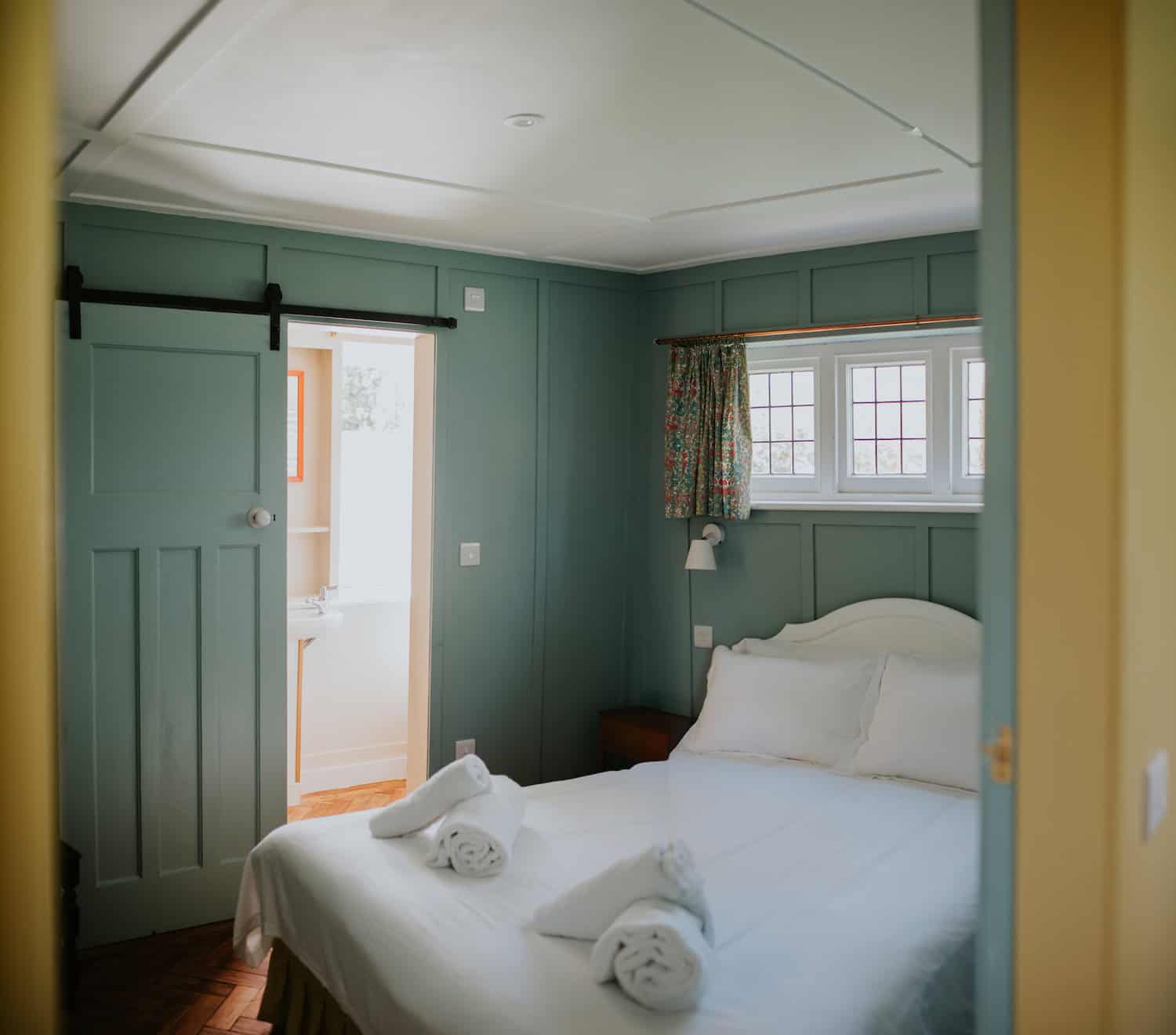 Bright Dorset coast bedroom with ocean glimpses, comfy bed, colourful curtains, ideal for seaside holidays.