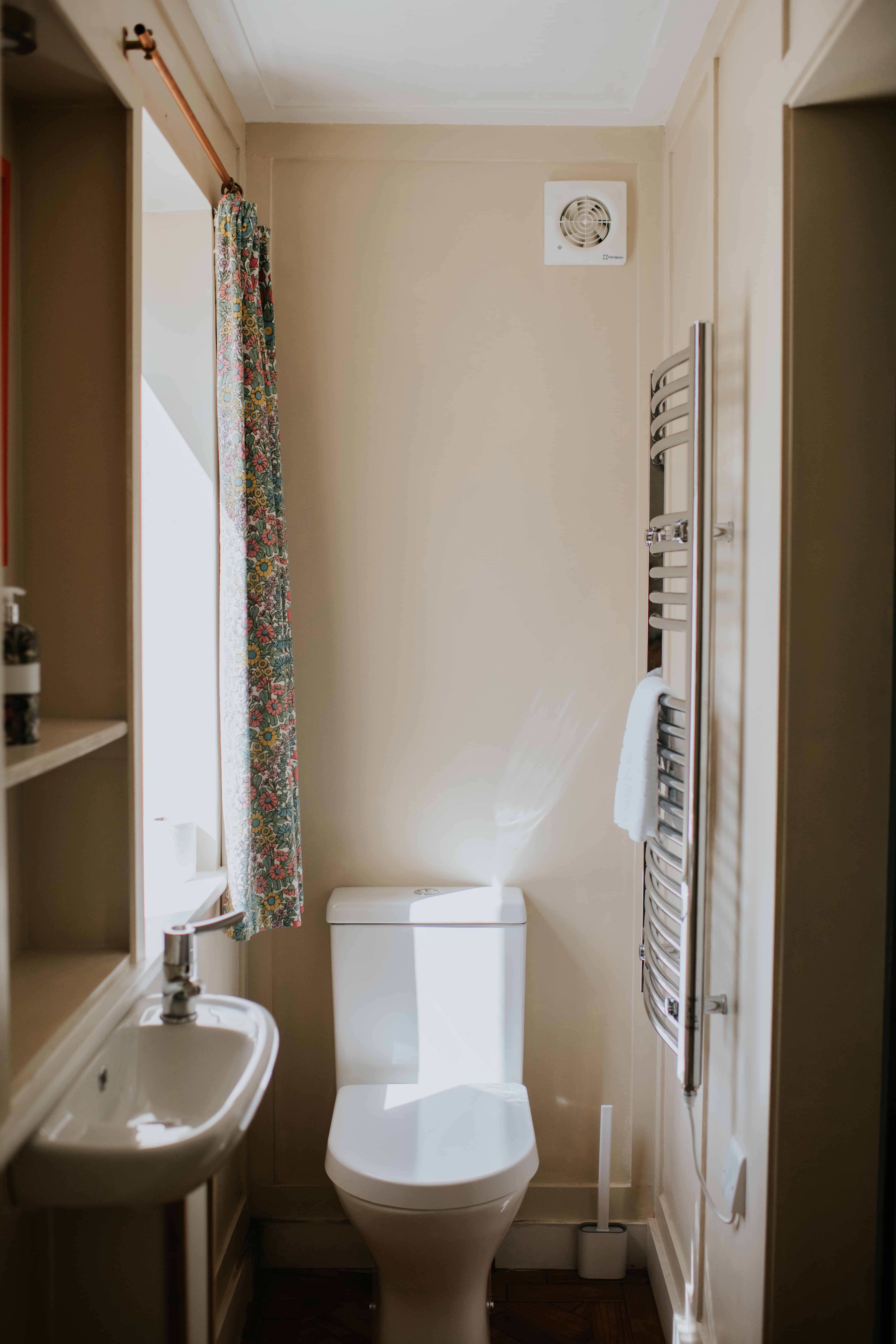 Bright bathroom with a beige wall, small sink, and heated towel rail at Rushay, Dorset coast.