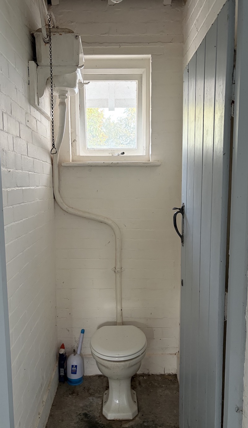 Outside loo with high level cistern and window